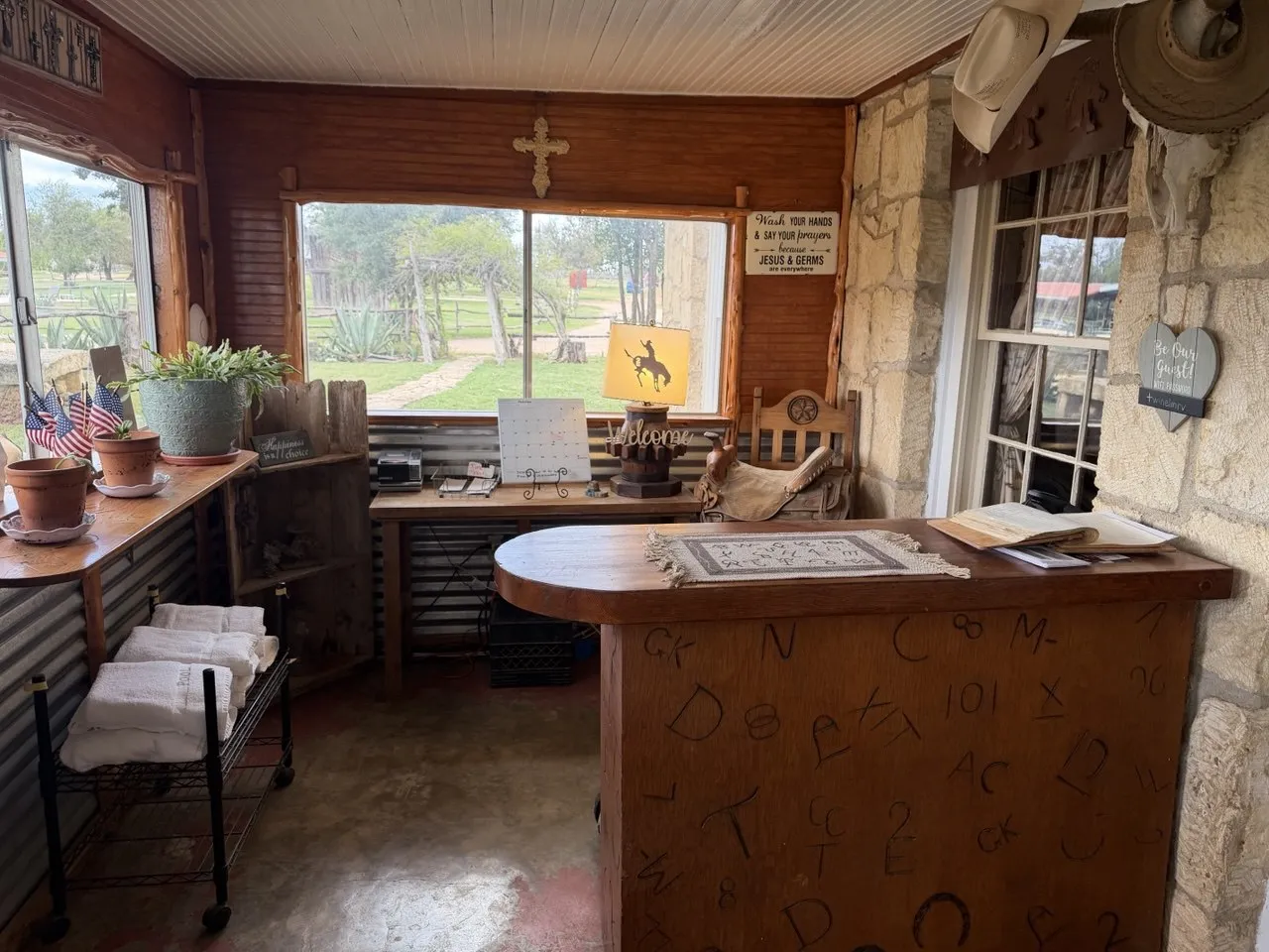 The front desk: a counter carved with ranch brands, a bronc lamp and a welcome sign