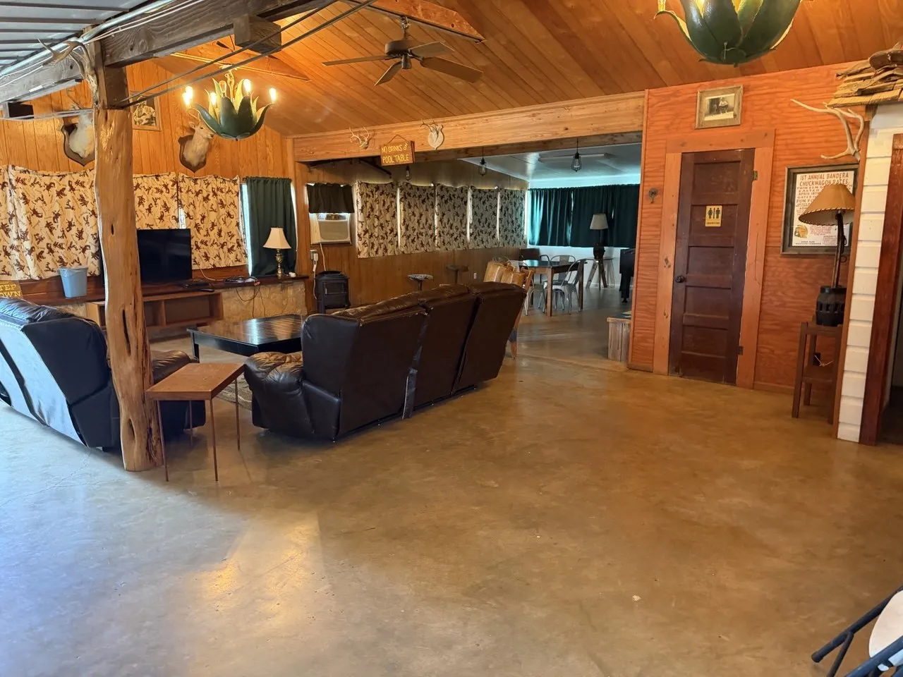 The lodge hall: leather sofas and a TV lounge under a wood ceiling, with the dining area beyond