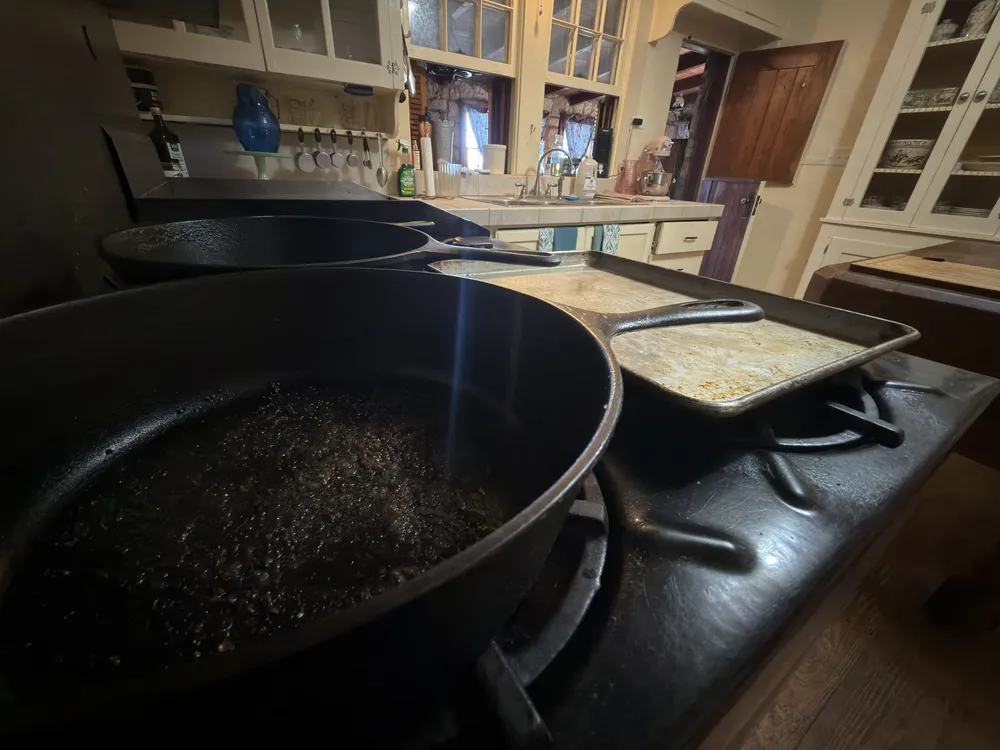 Oil bubbling in a big cast-iron skillet on the range, with a griddle beside it